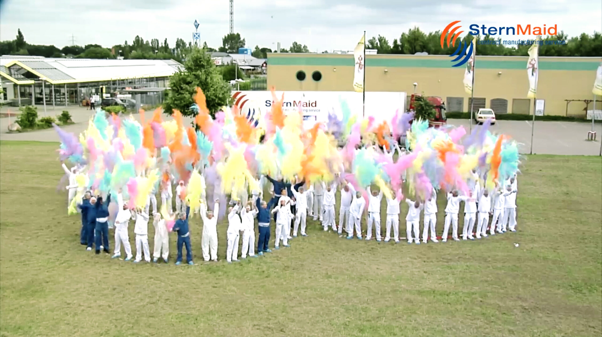 Mitarbeitende werfen Holi Pulver in die Luft